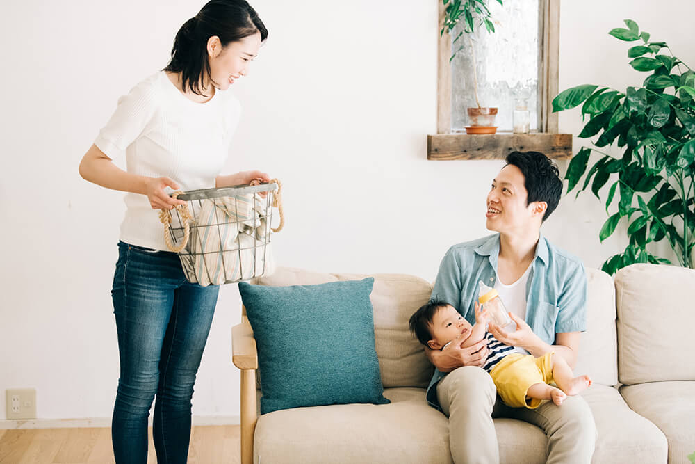 赤ちゃんを抱く夫と洗濯をする妻